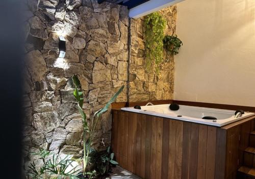 uma banheira num quarto com uma parede de pedra em Grinbergs Village Hotel em Socorro