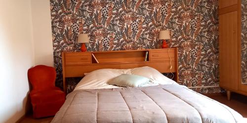 a bedroom with a large bed and a red chair at La Cadette des 2 Frangines in Mazerat-Aurouze