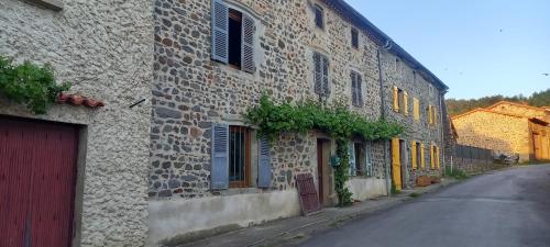 an old stone building with yellow doors and windows at La Cadette des 2 Frangines in Mazerat-Aurouze