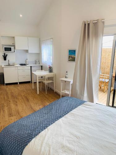 une chambre avec un lit et une cuisine avec une table dans l'établissement Charmante maisonnette neuve proche Thalasso, à Sainte-Marie de Ré