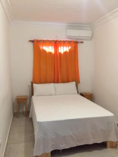 a bedroom with a bed with an orange curtain at Habitat Aparta Hotel Havaclub in Sánchez