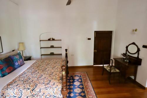 a bedroom with a bed and a table and a mirror at Bawlana Estate - Kandy in Kandy