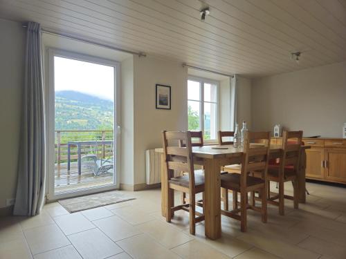 une salle à manger avec une table et des chaises et une grande fenêtre dans l'établissement La Maison Rose - La Bresse, à La Bresse