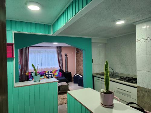 a kitchen with green walls and a living room at Departamento Constitución in Constitución