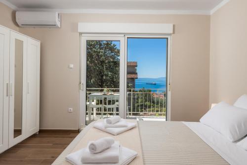 コストレナにあるSeaview Garden Premium apartmentsのベッドルーム1室(大きな窓、ベッドの上にタオル付)
