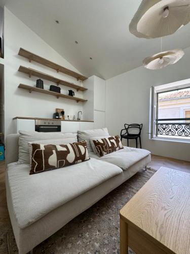 une chambre blanche avec un grand lit avec des oreillers dans l'établissement La Halte des Arènes de Nimes - Appartement Minimaliste - Ecusson Nimes, à Nîmes