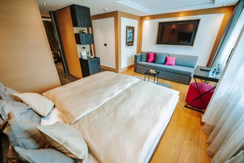 a bedroom with a large bed and a couch at Hotel Eden Wellness in Zermatt