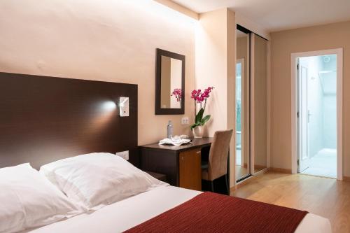 Un dormitorio con una cama y un escritorio con espejo. en Hotel Santiago Apóstol, en Santiago de Compostela
