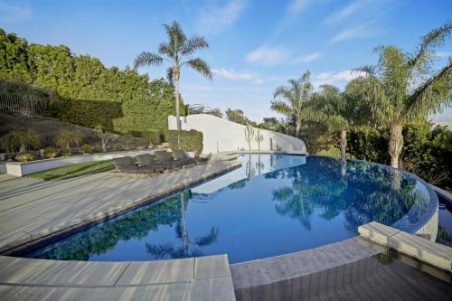 a swimming pool with blue water and palm trees at Winding Way in Malibu