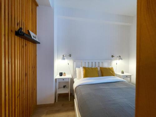 a bedroom with a bed with yellow pillows and two tables at Forest Oasis Studio - free Netflix and Disney Plus in Predeal