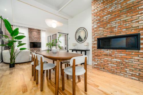 comedor con pared de ladrillo, mesa y sillas en Le 1911 Luxury Condo, en Quebec
