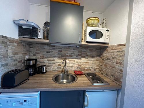 un comptoir de cuisine avec un évier et un micro-ondes dans l'établissement Studio cosy pour 2 pers, centre des Menuires, au pied des pistes - FR-1-452-273, aux Menuires