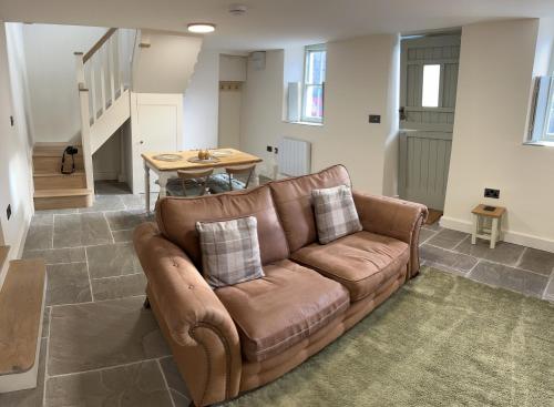 a brown couch in a living room with a table at Rose Cottage, Little Haven in Pembrokeshire