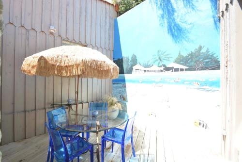 une table et des chaises en verre sous un parasol sur la terrasse dans l'établissement La villa Mauricia, à Lacanau-Océan