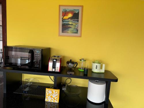a counter with a microwave on a yellow wall at Baskervilu Muiža in Sērenes