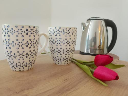 deux tasses à café et des fleurs rouges sur une table dans l'établissement Sweet Rooms San Francesco, à Naples