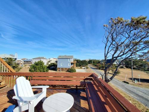 a deck with two white chairs and a wooden bench at Barney's Roost in Sanderling