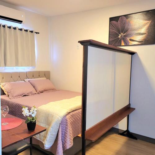 a small bedroom with a bed and a mirror at Perfeito Studio 22 in Poços de Caldas