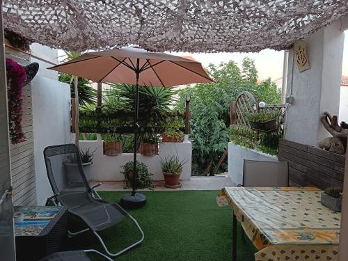 a patio with an umbrella and a table and chairs at Chambre les flamants, climatisation, avec vue imprenable sur les étangs, petit déjeuner offert in Saintes-Maries-de-la-Mer