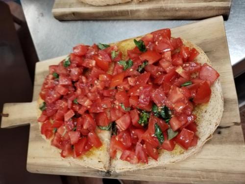 a pizza with tomatoes on top on a cutting board at Camping Roma in Ventimiglia