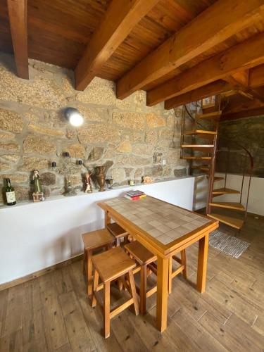 a wooden table and chairs in a room with a stone wall at Casa da iapa in Soajo