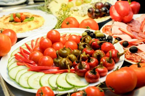 a table topped with plates of food with tomatoes and cucumbers at Myo Hotel Mysterius in Prague