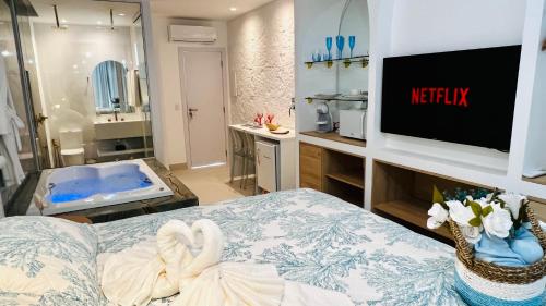 a hotel room with a tv and a bed and a bathroom at D'Blue Búzios Hotel Boutique in Búzios