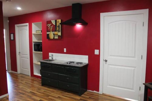 a kitchen with red walls and a black island in a room at Cozy Lodge Suite in Sylvan Lake