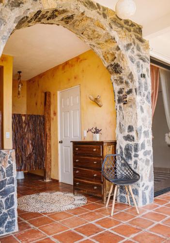 a room with a stone wall with a dresser and a chair at Casa Jasmin Bed & Breakfast in Troncones