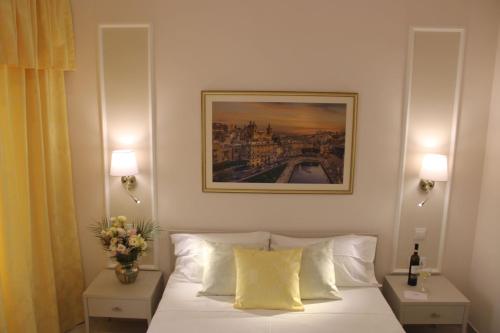 a bedroom with a white bed with a painting on the wall at North Lodge by PetitChic in Mellieħa