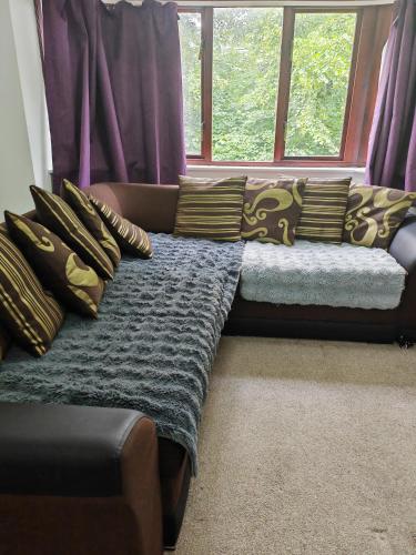a couch sitting in front of a window with pillows at Spacious flat with free parking in Croydon in Croydon