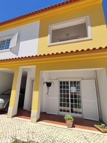 a yellow and white house with a garage at Casa das Rosas - Moradia com jardim e churrasco, Charneca da Cotovia in Sesimbra