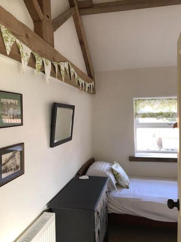 a small bedroom with a bed and a window at The Barn in Tollerton