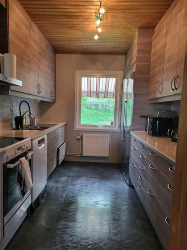 a large kitchen with wooden cabinets and a window at Villa Tenhult in Tenhult