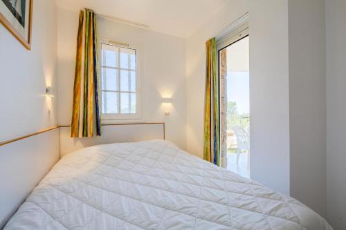 une chambre blanche avec un lit et une fenêtre dans l'établissement Résidence le Hameau de Cap Esterel - maeva Home - Appartement 2 pièces 4 personnes - Prestige MAE-6441, à Saint-Raphaël