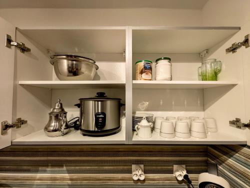 a kitchen cabinet filled with pots and pans and appliances at Maison Cosy in Saint-Denis