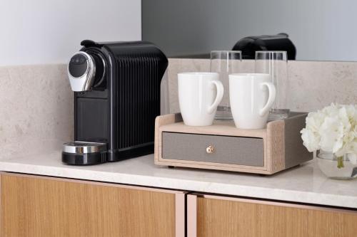 a kitchen counter with a coffee maker and two cups at Mövenpick Hotel & Apartments Ghala Muscat in Muscat
