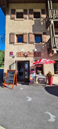 a building with an umbrella and a sign in front of it at Hôtel et Appart'Hôtel Restaurant L'Adray in Longefoy