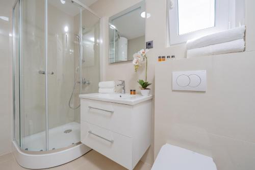 a white bathroom with a shower and a sink at Bliss Apartments in Sutomore