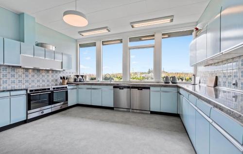 a large kitchen with white cabinets and large windows at Gorgeous Home In Glesborg in Glesborg