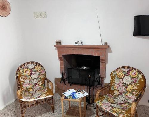 a living room with two chairs and a fireplace at La Baita dei Sibillini in Ceretana