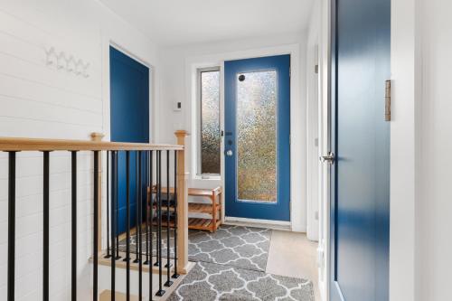 a hallway with a blue door and a staircase at The Cozy Woodpecker Cottage in Notre-Dame-de-l'Île-Perrot
