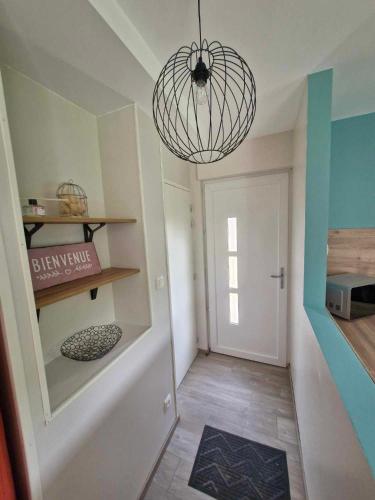 un couloir avec une porte et un lustre dans l'établissement Maison de la Butte de Thil, à Nan-sous-Thil