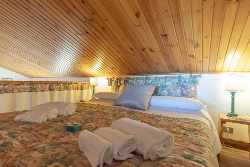 a large bed in a room with a wooden ceiling at Chalet Aria Sottile in Sassotetto