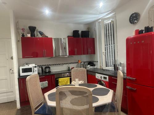 une cuisine avec des placards rouges et une table avec des chaises dans l'établissement Nido, à Saint-Denis