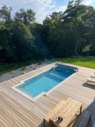 - une piscine sur une terrasse avec une table dans l'établissement Villa avec piscine en Baie Mont St Michel dans un parc arboré, à Le Val-Saint-Père