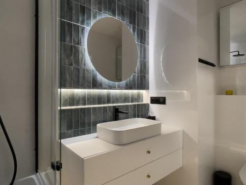 a bathroom with a white sink and a mirror at URBAN APARTMENTS PREMIUM Baildona No 11 FREE GARAGE, Self CHECK-IN in Katowice