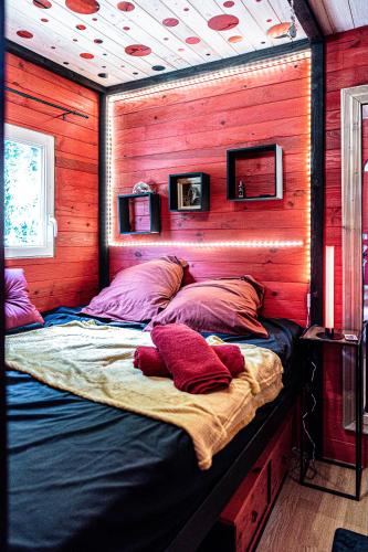 un grand lit dans une chambre aux murs en bois dans l'établissement la Pangée roulottes hébergements insolites, à Lansac
