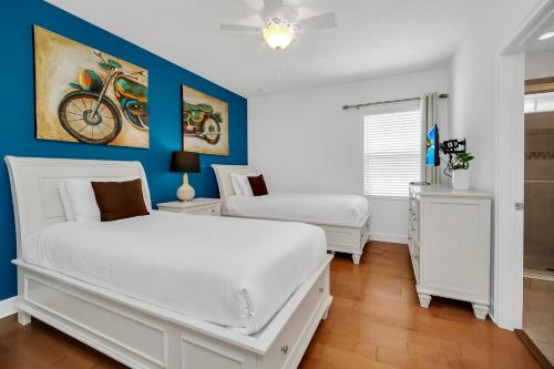 a bedroom with two white beds and a blue wall at The Carpe Diem in Orlando