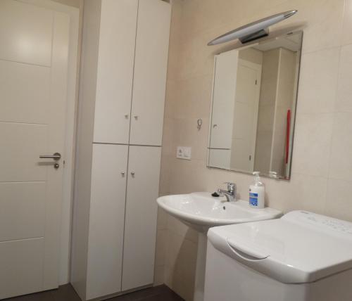 Baño blanco con lavabo y espejo en Málaga Apartamentos - Montaño, 18, en Málaga